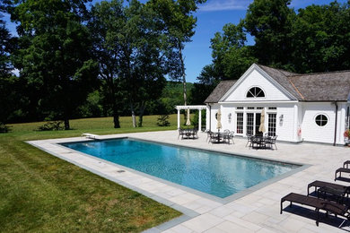 Ejemplo de piscina alargada clásica de tamaño medio rectangular en patio trasero con adoquines de piedra natural