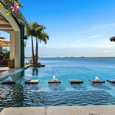 Pool fountain - tropical backyard tile and custom-shaped infinity pool fountain idea in New York