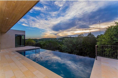 Photo of a medium sized contemporary back rectangular infinity swimming pool in Austin with concrete paving.