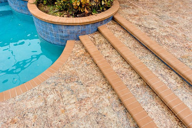 Modelo de piscinas y jacuzzis mediterráneos grandes a medida en patio trasero con adoquines de piedra natural