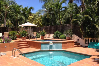 Foto de piscina con fuente natural tropical de tamaño medio a medida en patio con suelo de baldosas