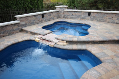 Идея дизайна: большой бассейн произвольной формы на заднем дворе в стиле неоклассика (современная классика) с джакузи и мощением клинкерной брусчаткой