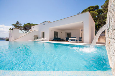 Esempio di una piscina a sfioro infinito mediterranea con fontane
