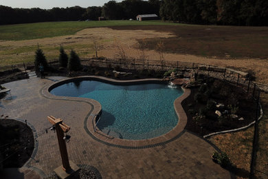 Large trendy backyard brick and custom-shaped natural pool landscaping photo in St Louis