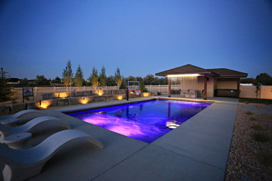 Foto de piscina con fuente alargada actual de tamaño medio rectangular en patio trasero con losas de hormigón