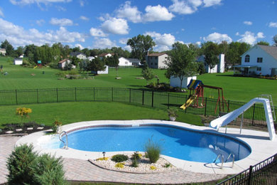 Esempio di una grande piscina monocorsia personalizzata dietro casa con un acquascivolo e pavimentazioni in cemento