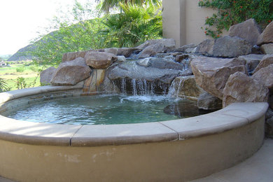 Small tuscan backyard stone and custom-shaped natural hot tub photo in Orange County