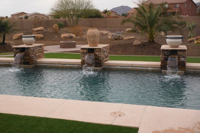 フェニックスにある広いサンタフェスタイルのおしゃれな裏庭プール (噴水、デッキ材舗装) の写真