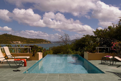 Example of a backyard tile and rectangular infinity pool design in Other
