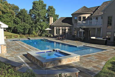 Large classic back custom shaped natural hot tub in Philadelphia with natural stone paving.