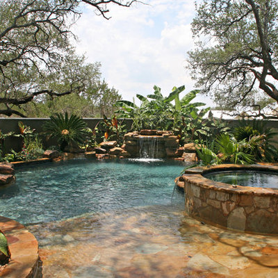 Hot tub - mid-sized tropical backyard stone and custom-shaped natural hot tub idea in Austin