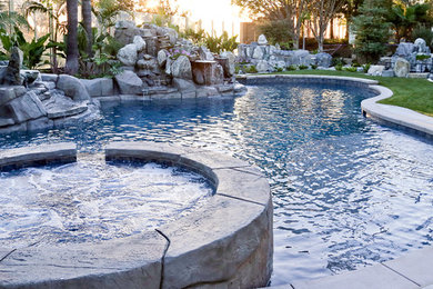 Large island style backyard stone and custom-shaped natural hot tub photo in Orange County