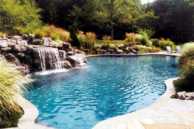 Design ideas for a back custom shaped swimming pool in New York with a water feature and natural stone paving.