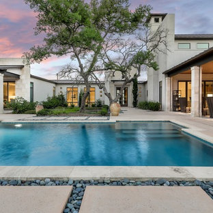 Immagine di una piscina monocorsia design rettangolare dietro casa con fontane e lastre di cemento