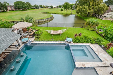 Mittelgroßer Pool hinter dem Haus in rechteckiger Form mit Natursteinplatten in Houston