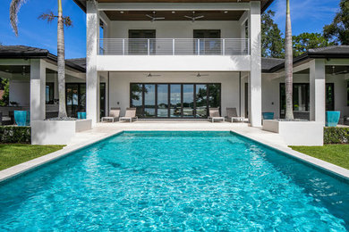 Modern back rectangular swimming pool in Tampa with natural stone paving.