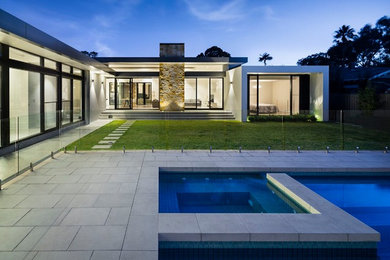 Imagen de piscinas y jacuzzis alargados actuales de tamaño medio rectangulares en patio trasero con adoquines de hormigón