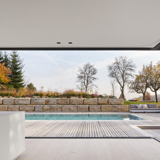 Immagine di una grande piscina monocorsia moderna rettangolare dietro casa con pedane