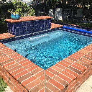 Design ideas for a small traditional backyard rectangular pool in Orange County with a water feature and brick pavers.