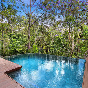 Photo of a mid-sized contemporary backyard rectangular infinity pool in Brisbane with decking.