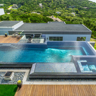 Immagine di una grande piscina a sfioro infinito minimalista personalizzata in cortile con fontane e pedane