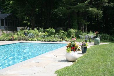 Imagen de piscina alargada clásica grande rectangular en patio trasero con adoquines de piedra natural