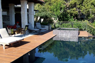 Modelo de piscina con fuente infinita actual de tamaño medio rectangular en patio trasero con entablado