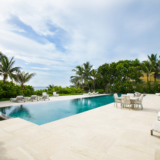 Huge trendy backyard stone and rectangular infinity pool photo in Miami