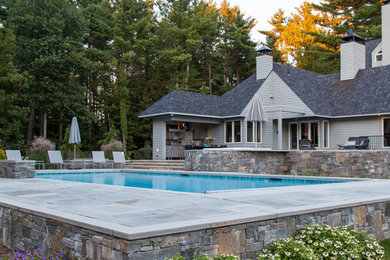 Diseño de piscina alargada actual grande rectangular en patio trasero con adoquines de piedra natural