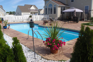 Imagen de piscina costera de tamaño medio a medida en patio trasero con suelo de hormigón estampado