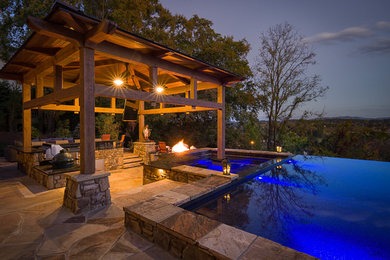 Pool house - large rustic backyard stone and rectangular infinity pool house idea in Charlotte
