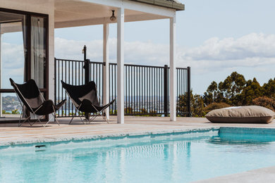 Diseño de piscina costera de tamaño medio rectangular en patio lateral con adoquines de piedra natural