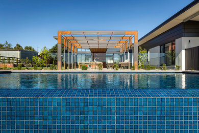 Aménagement d'une grande piscine à débordement et arrière contemporaine rectangle avec des pavés en pierre naturelle.