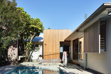 Aménagement d'une piscine naturelle et arrière rétro de taille moyenne et rectangle avec des pavés en béton.