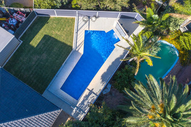Foto de piscina con fuente alargada contemporánea grande a medida en patio trasero con granito descompuesto