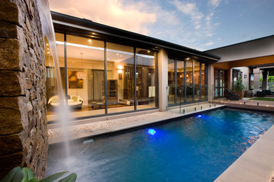 Ejemplo de piscina con fuente actual de tamaño medio rectangular en patio con entablado