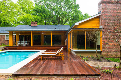 Modelo de piscina alargada moderna de tamaño medio rectangular en patio trasero con entablado