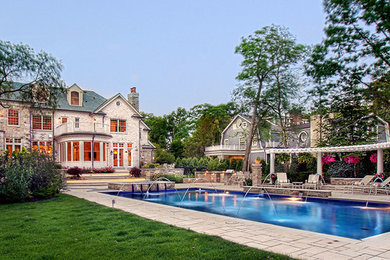 Imagen de piscina con fuente alargada clásica grande rectangular en patio trasero con adoquines de hormigón