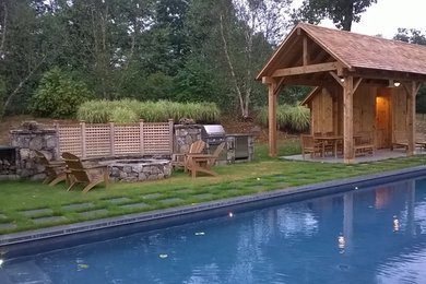 Ejemplo de casa de la piscina y piscina rústica de tamaño medio rectangular en patio trasero con adoquines de piedra natural