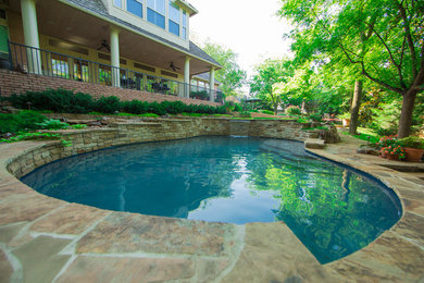 Modelo de piscina con fuente natural tradicional renovada grande a medida en patio trasero con adoquines de piedra natural