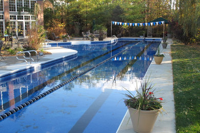 Immagine di un'ampia piscina monocorsia tradizionale a "L" dietro casa con lastre di cemento