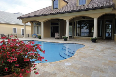 Large elegant backyard tile and custom-shaped pool photo in Miami