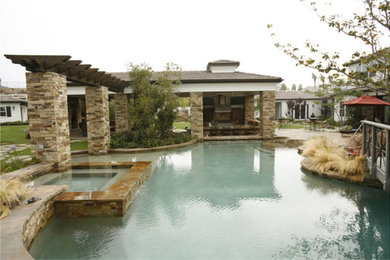 Inspiration for a large timeless backyard stone and custom-shaped natural hot tub remodel in Orange County
