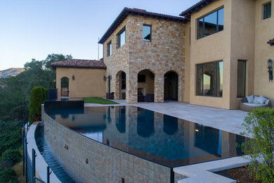 Imagen de piscinas y jacuzzis infinitos minimalistas de tamaño medio a medida en patio trasero con adoquines de piedra natural