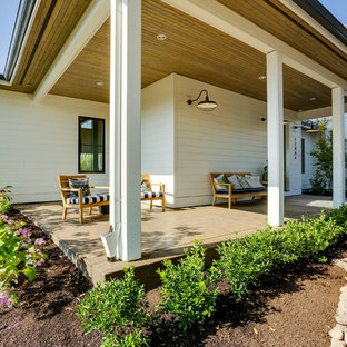 Immagine di un ampio portico country davanti casa con un tetto a sbalzo