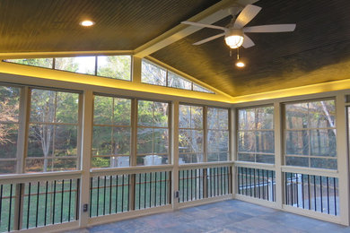 Mid-sized classic stamped concrete screened-in back porch idea in Raleigh with a roof extension