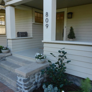 Immagine di un portico stile americano di medie dimensioni e davanti casa con un giardino in vaso, lastre di cemento e un tetto a sbalzo