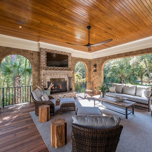 Idee per un grande portico american style dietro casa con un caminetto, pedane e un tetto a sbalzo