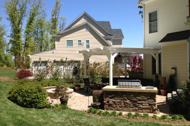 Modelo de terraza clásica de tamaño medio en patio trasero con adoquines de ladrillo y pérgola