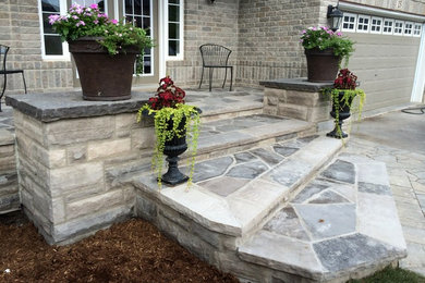 Ejemplo de terraza clásica de tamaño medio en patio delantero y anexo de casas con adoquines de piedra natural